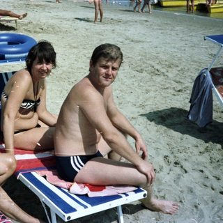 People relaxing on a crowded beach with a sea view.