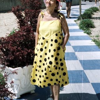 Woman stands on a pathway near a hotel and beach.