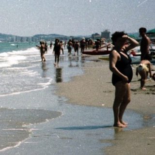 People on a beach with waves and blue sky.