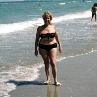 People on a beach with a woman walking toward the camera.