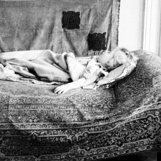 Child lies asleep on a patterned sofa.