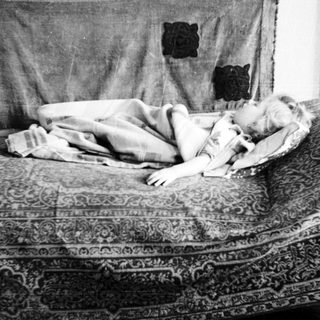 Child lies asleep on a patterned sofa.