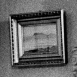 Woman in dress adjusting it in front of a mirror.