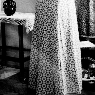 Woman in dress adjusting it in front of a mirror.
