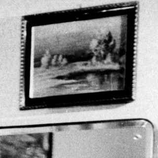 Woman stands before a mirror in a patterned dress.