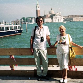 Couple poses near water with San Giorgio Maggiore in background.