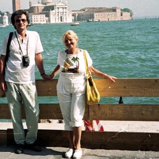 Couple poses near water with San Giorgio Maggiore in background.