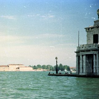 Venice, Italy, featuring boats, buildings, and a cloudy sky.