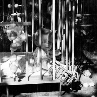 Black and white photo of a baby in a crib.
