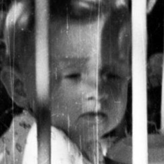 Black and white photo of a baby in a crib.