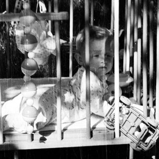Black and white photo of a baby in a crib.