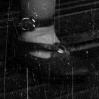 Here's a brief summary of the image: A young child stands reaching for a door handle.