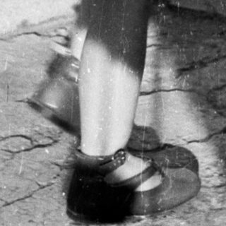 Here's a brief summary of the image: Young child stands with a cup, casting a shadow.