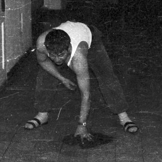 Man in a hallway, appearing to inspect the floor.
