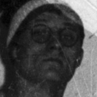 Man in jumpsuit stands in room with blue detail.