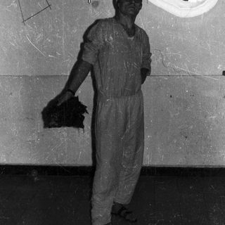 Man in jumpsuit stands in room with blue detail.