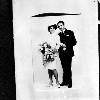 Couple in formalwear poses with flowers, likely a wedding.