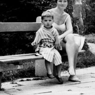 Here's a brief summary of the image: Woman and child sit on a bench in a garden.