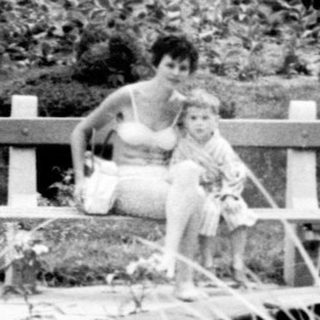 Person sitting on a bench in a garden setting.