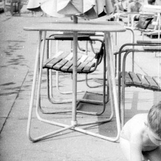 Here's a brief summary of the image: Child playing with a ball near a pool area.