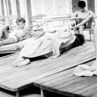 Black and white photo of people on sun loungers.