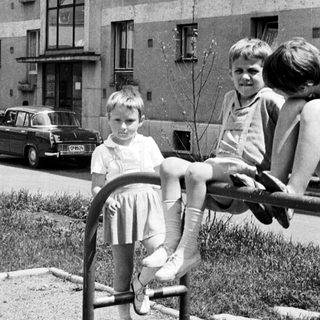 Children playing on a playground in front of a building.