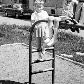 Children playing on a playground in front of a building.