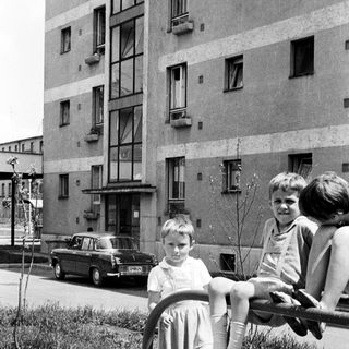 Children playing on a playground in front of a building.