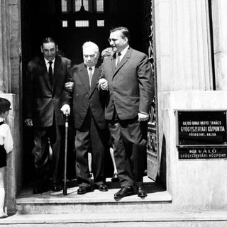 Here's a brief summary of the image: Three men exit a building; a boy watches nearby.