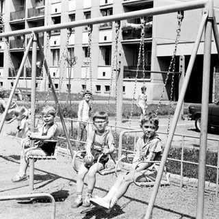 Black and white photo of children playing on swings.