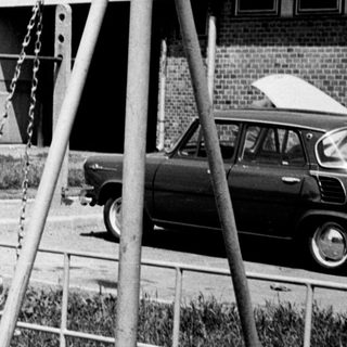 Black and white photo of children playing on swings.