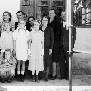 Group portrait of a family standing outside a house.