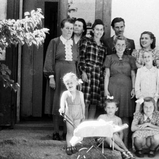 Group portrait of a family standing outside a house.