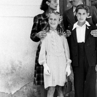 A woman and two children stand outside a building.