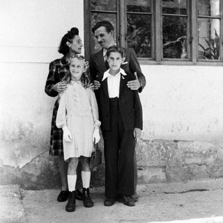 A woman and two children stand outside a building.