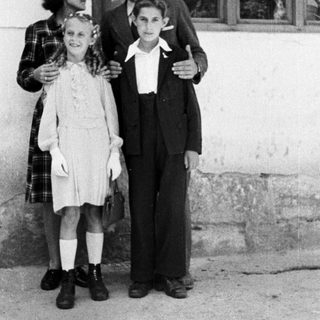 A woman and two children stand outside a building.