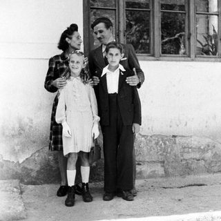 A woman and two children stand outside a building.