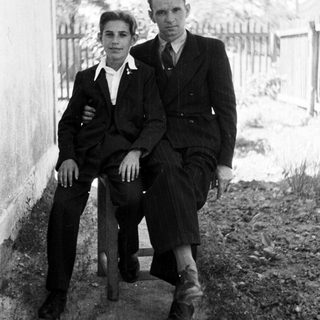 Black and white photo of two men seated outdoors.