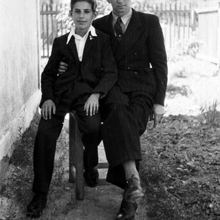 Black and white photo of two men seated outdoors.