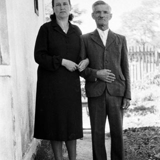 Black and white photo of an elderly couple standing outside.