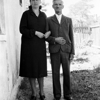 Black and white photo of an elderly couple standing outside.