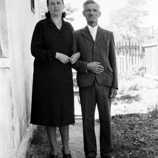 Black and white photo of an elderly couple standing outside.