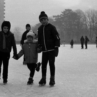Children ice skating on a frozen pond, winter scene.