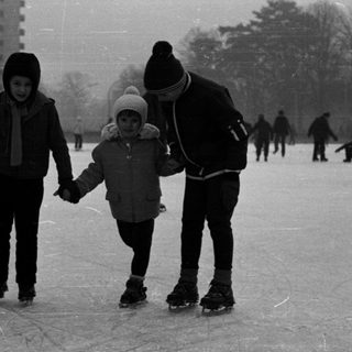 People ice skating on a frozen pond, wintry scene.