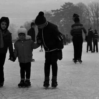 People ice skating outdoors on a frozen pond.