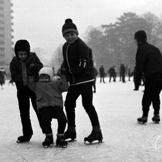 People ice skating outdoors on a winter day.