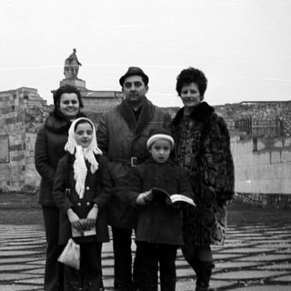 Family portrait with a large wall and monument in background.