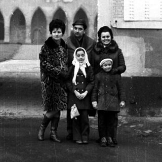 Family stands outside a museum with an arched entrance.