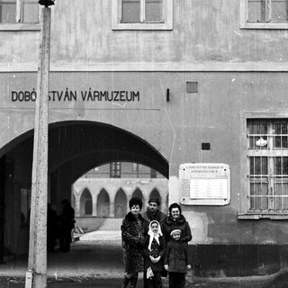 Family stands outside a museum with an arched entrance.