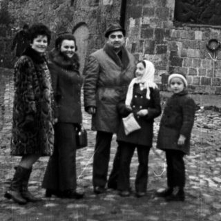 Family poses in front of a stone archway and wall.